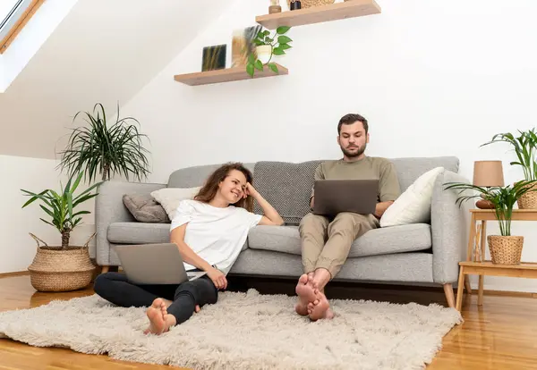 Evdeki genç çift dizüstü bilgisayarlarını otel araması ve rezervasyon için kullanıyor..