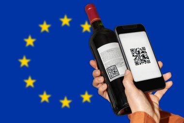 Şarap ürünlerinin AB 'de e-etiketlenmesi. Şarap şişesi etiketindeki QR kodunu tarayan kişi Avrupa Birliği 'nin önünde cep telefonu kullanıyor.. 