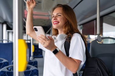 Şehirli otobüsle seyahat ederken akıllı telefonunu kullanan kırmızı dudaklı çekici esmer kadın..