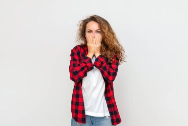 Genç kıvırcık saçlı, esmer kadın, ellerini şaşkın duygularıyla ağzını kapatıyor..