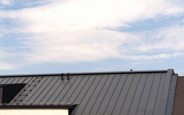 Metal çatı kaplaması. Gökyüzünün önündeki çatı..