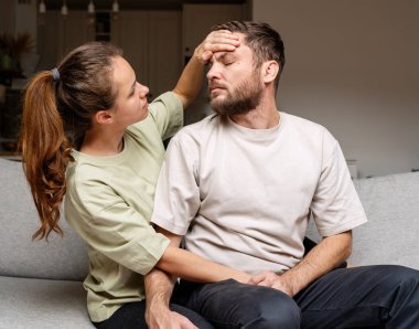 Aile bakımı. Kadın elini kocasının alnına koyar ve sıcaklığı elleriyle ölçer..