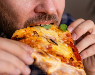 Pizza yiyen bir adamın yakın plan fotoğrafı..