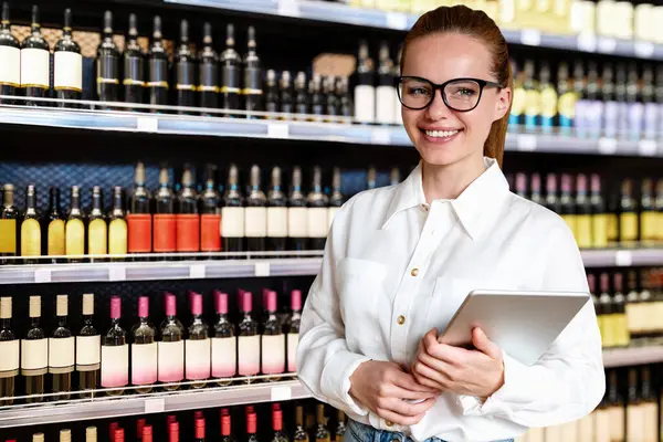 Woman director or manager of liquor store or supermarket. Businesswoman with digital tablet working in wine shop.