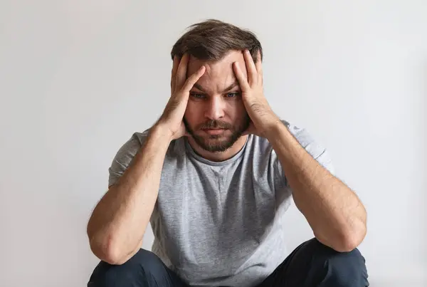 Erkek akıl hastalığı konsepti. Yorgun ve mutsuz bir adam elleriyle başını tutuyor. Melankoli ve yıkılmış kişi.