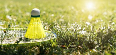 Çimlerin yeşil çimlerinde sarı badminton raketi.