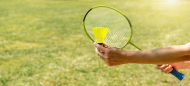 Dışarıda, yeşil çimlerin üzerinde badminton oynuyorum..
