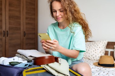 İnternetten bir otel kiralamak ve akıllı telefondan e-bilet almak. Kadın seyahate hazırlanıyor..