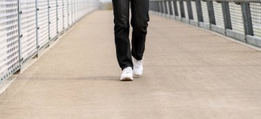 Şehirde yaya köprüsünde yürüyorum. Ayaklar hareket halinde beyaz spor ayakkabılarda.