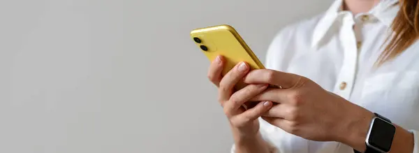 Online messaging. E-commerce and electronic banking. Golden coloured mobile phone in hands of businesswoman.
