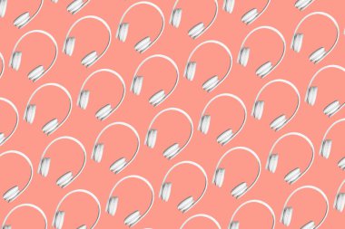 Şeftali rengi arka planda beyaz kablosuz kulaklıkların modern deseni.