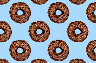 Mavi arka planda delikleri olan çikolatalı donutların yaratıcı deseni.