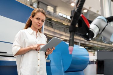 Genç bayan girişimci, kablosuz teknolojiyi kullanarak başlangıç fabrikasında robot kolu kontrol ediyor..