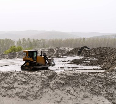 Kum fabrikasında çalışan buldozer. Nehirden gelen kum madenciliği.