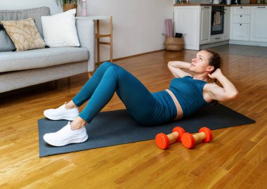 Spor kıyafetli bir kadın evde karın kası egzersizi yapıyor. Ab egzersizi.