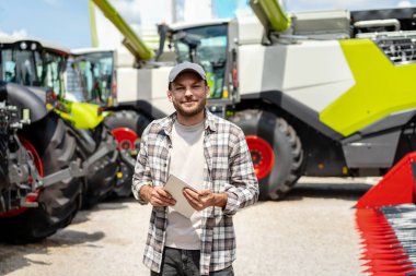 Gülümseyen bir çiftçi bayilikten almak için yeni bir biçerdöver seçer. Tarım makinelerinin kiralanması.