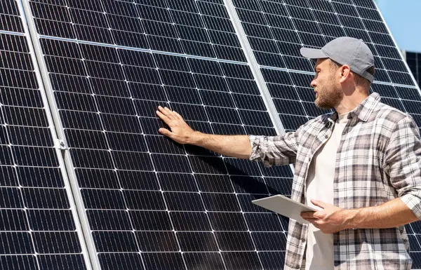 Güneş enerjisi santralinin incelenmesi... Güneş panellerinin bakımı. İnsan mühendisi güneş panelinin yüzeyine dokunuyor.