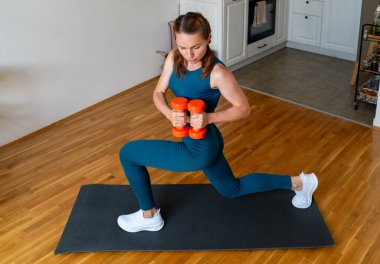 Atletik kadın evde iki dambılla antrenman yapıyor..