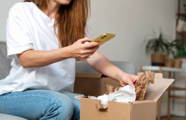 Kadın paketleri evde açıyor ve internetten sipariş veriyor. Teslimat servisinin geri bildirimi paylaşılıyor.