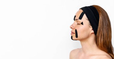 Saç bandı takan kadın güzellik modeli beyaz arka planda yüz hatları bandı uyguluyor 