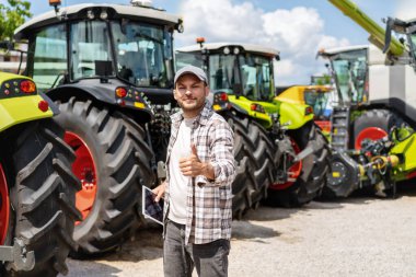 Adam traktörlerin önünde duruyor ve el kol hareketi yapıyor..