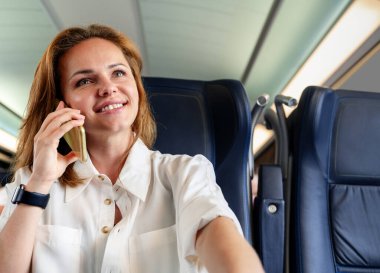 İş kadını uçakta uçarken telefonda konuşuyor..