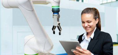 Üretimde robotik ve otonom teknolojik çözüm. Bir iş kadını dijital tabletini kullanarak bir robotik kolun performansını analiz eder..