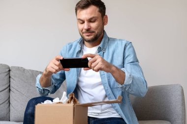 Kot gömlekli bir erkek cep telefonuyla internetten sipariş veriyor. İnternet siparişi açılıyor.