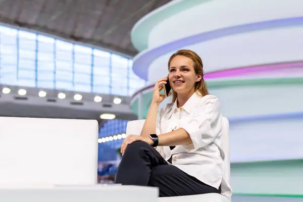 stock image Confident young businesswoman sits in the hall of business centre and talking her mobile phone.