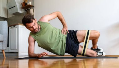 Kalas giymiş bir adam yoga minderinde ayak dayanıklılığı eğitimi için bant kullanıyor..