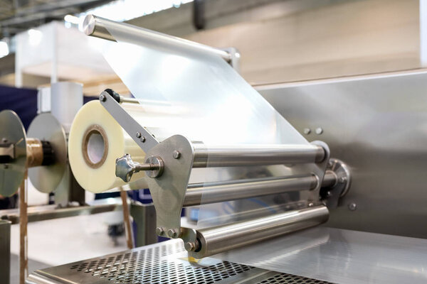 Крупный план рулона промышленной пластиковой пленки в упаковочных машинах. Полиэтиленовая пленка.
