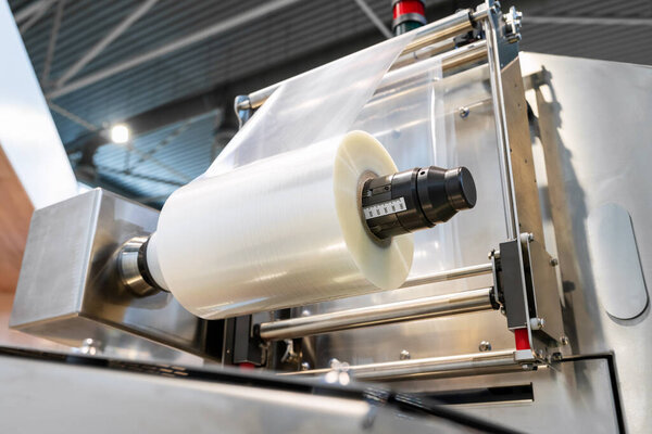 Пластиковая пленка, упаковочная промышленная машина на заводе. Ролик полиэтиленовой пленки.