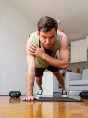 Adam kalas pozisyonunda kol kıvırma egzersizi yapıyor. Ev çalışması. 