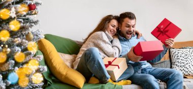 Genç, evli bir çift evdeki koltukta Noel hediyelerini açıyor.. 