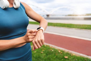 Bulanık koşu arka planında akıllı saat takibi yapan kadın koşucu bileği...