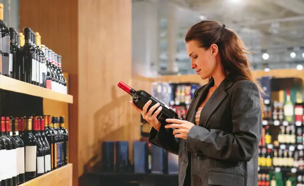 Esmer kadın şarap dükkanında şarap etiketini öğreniyor..