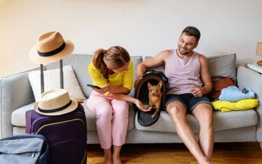 Küçük köpekleri ile genç beyaz bir çift seyahat, seyahat çantaları ve yolculuk hazırlığı için hazırlanıyor..