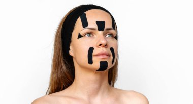 Yüzünde siyah kineziyoloji bantları olan beyaz bir kadının güzel portresi..