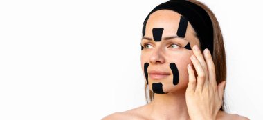 Yüzüne siyah kineziyoloji bantları yapıştıran beyaz bir kadının güzel portresi..