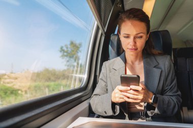 İş seyahati. İş kadını trenle seyahat ederken akıllı telefonuyla mesaj atıyor..