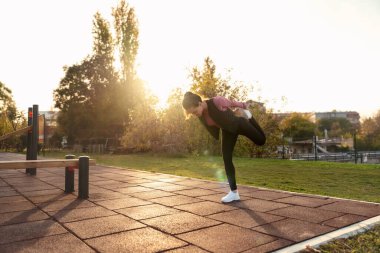 Dışarıda egzersiz yaparken esneme egzersizleri yapan genç bir kadın. Koşudan önce ısınan kadın koşucu.