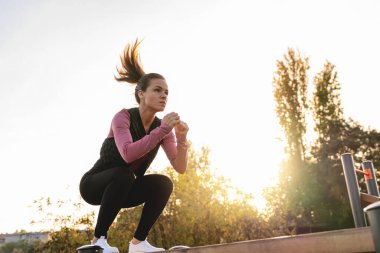 Genç beyaz bir kadın spor alanında dinamik egzersizler yapıyor, atlama egzersizi yapıyor..