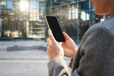 Şehir merkezindeki iş kadınının elindeki akıllı telefonun boş ekranı..