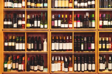 Ahşap perakende vitrininde boş etiketli şarap şişelerinin önü..