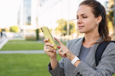 Şehrin caddesinde akıllı telefonunu kullanan beyaz bir kadın..