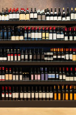Şarap şişelerinin dikey arkaplanı bir içki dükkanında raflarda sergileniyor..