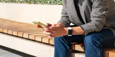 Şehir yaşam tarzında dijital cihazlar. Modern iş kadını şehir sokaklarında akıllı telefondan mesaj atıyor..