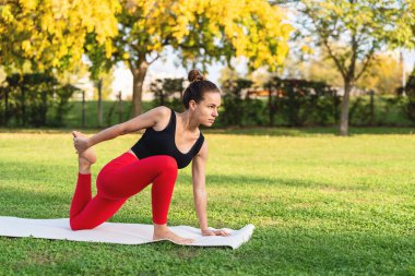 İnsanlar sağlıklı bir yaşam tarzı ve açık hava egzersizleri. Kadın parkta yoga minderinde geriniyor..