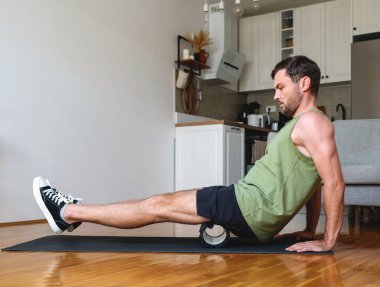 Beyaz adam evde köpük silindir kullanarak spor yapıyor..