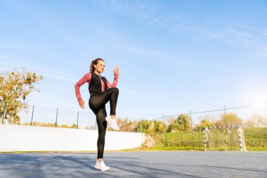 Formda bir kadının yaz aylarında spor sahasında egzersiz yapması düşük açılı bir manzara.